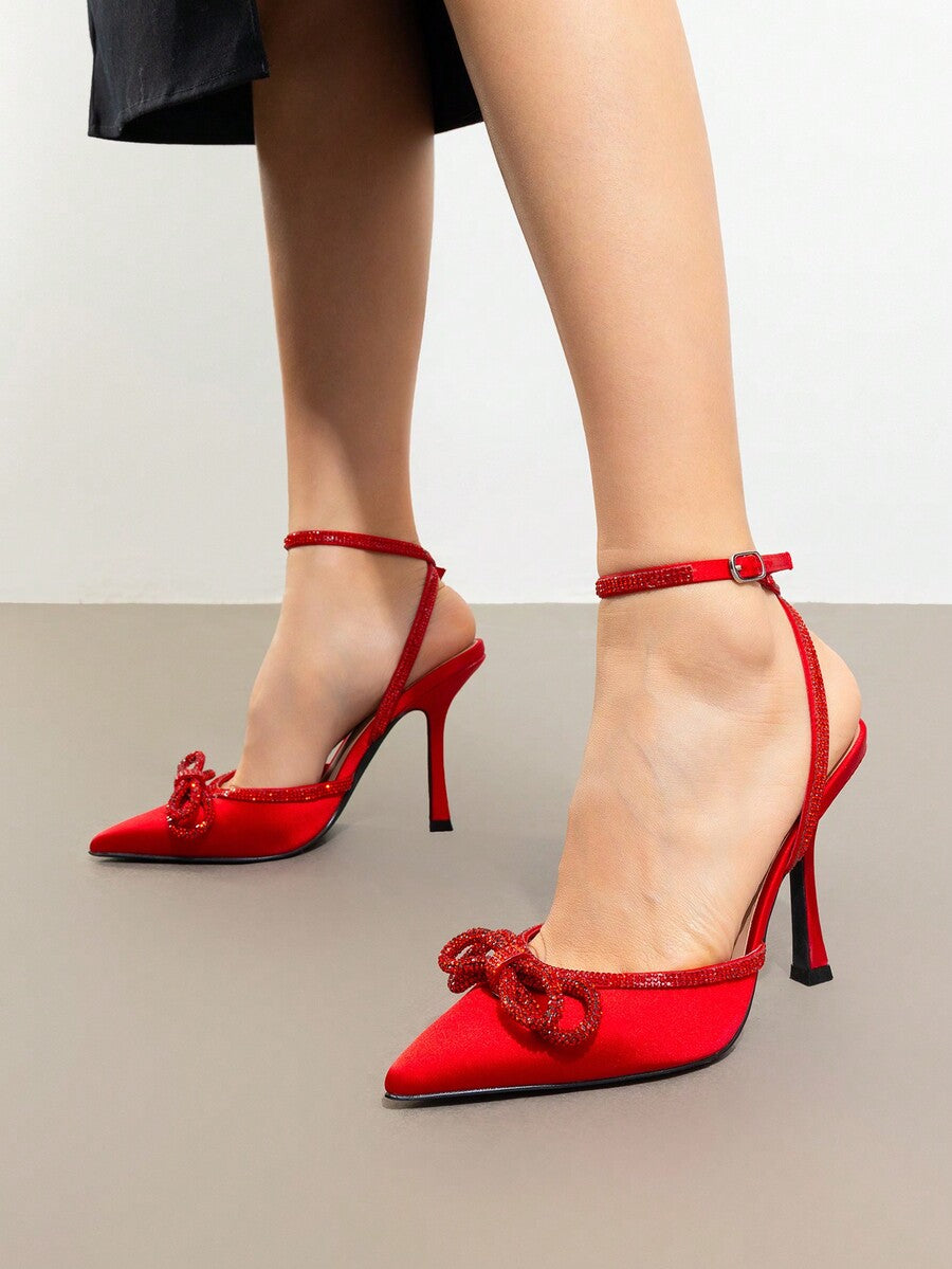 Women's rhinestone ankle strap high heels with pointed closed toe, strappy bow details, and stiletto heel for wedding and prom wear.