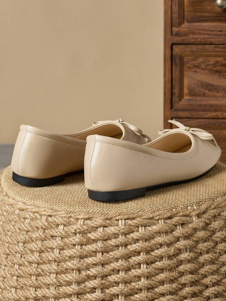 Pair of women's square toe slip-on flat shoes featuring a delicate bow detail and low vamp design.