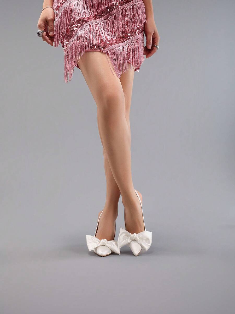 White pointed toe high heel stiletto sandals featuring lace patchwork, fringe trim, and an oversized bowknot accent.