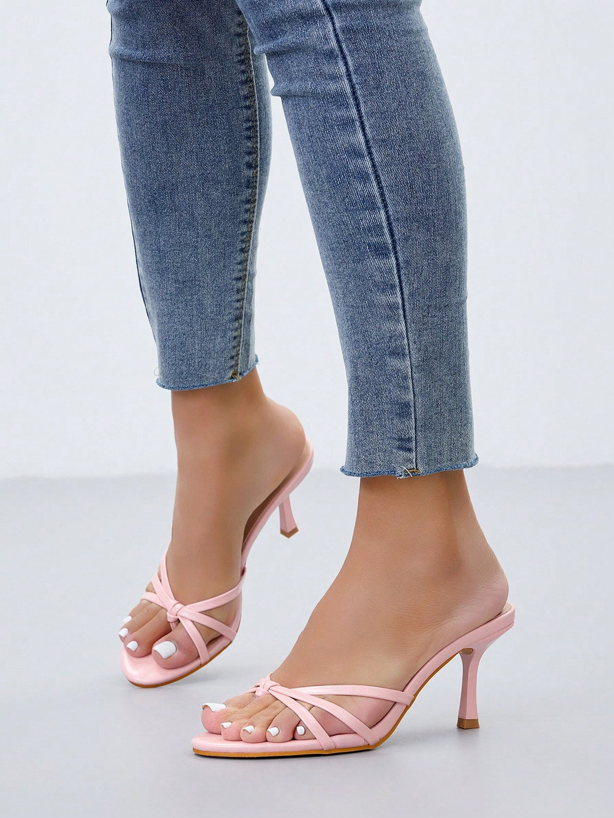 Women's slip-on stiletto heel platform sandals featuring a twist toe-post strap design and sleek finish.