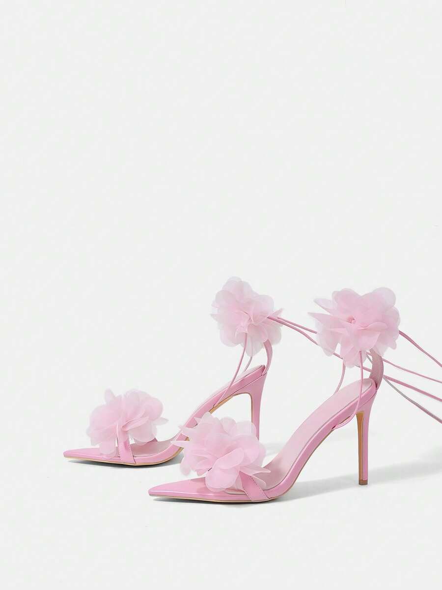 Women's open toe heeled sandals featuring 3D floral decor, satin lace-up ankle straps, and stiletto high heels.