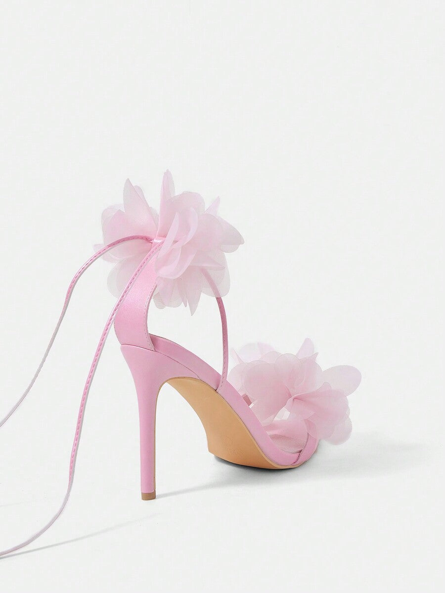 Women's open toe heeled sandals featuring 3D floral decor, satin lace-up ankle straps, and stiletto high heels.