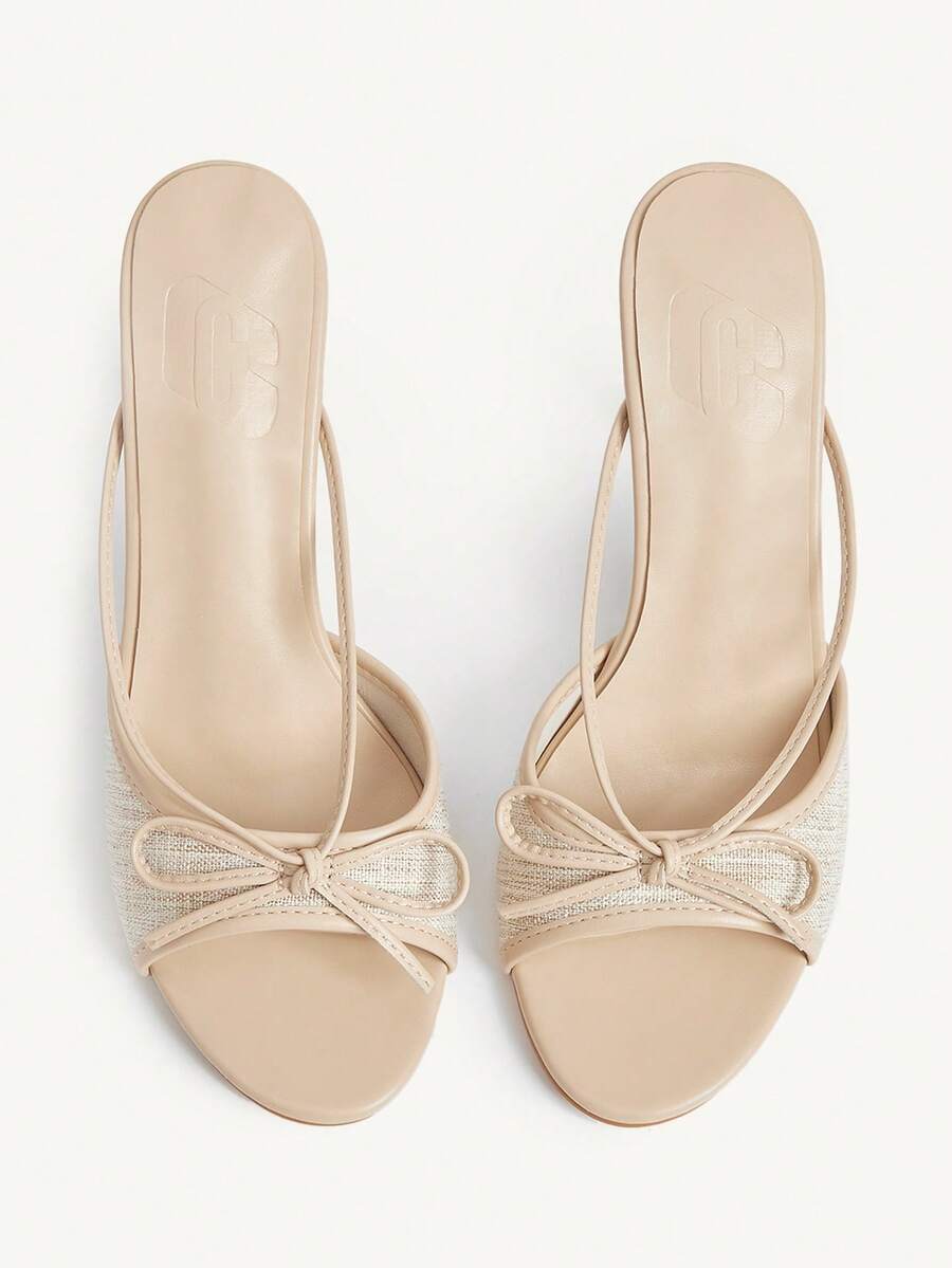 Elegant high heel sandals with romantic bow strap and slim stiletto heel for party and wedding occasions.