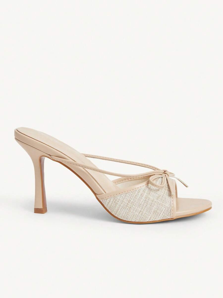 Elegant high heel sandals with romantic bow strap and slim stiletto heel for party and wedding occasions.