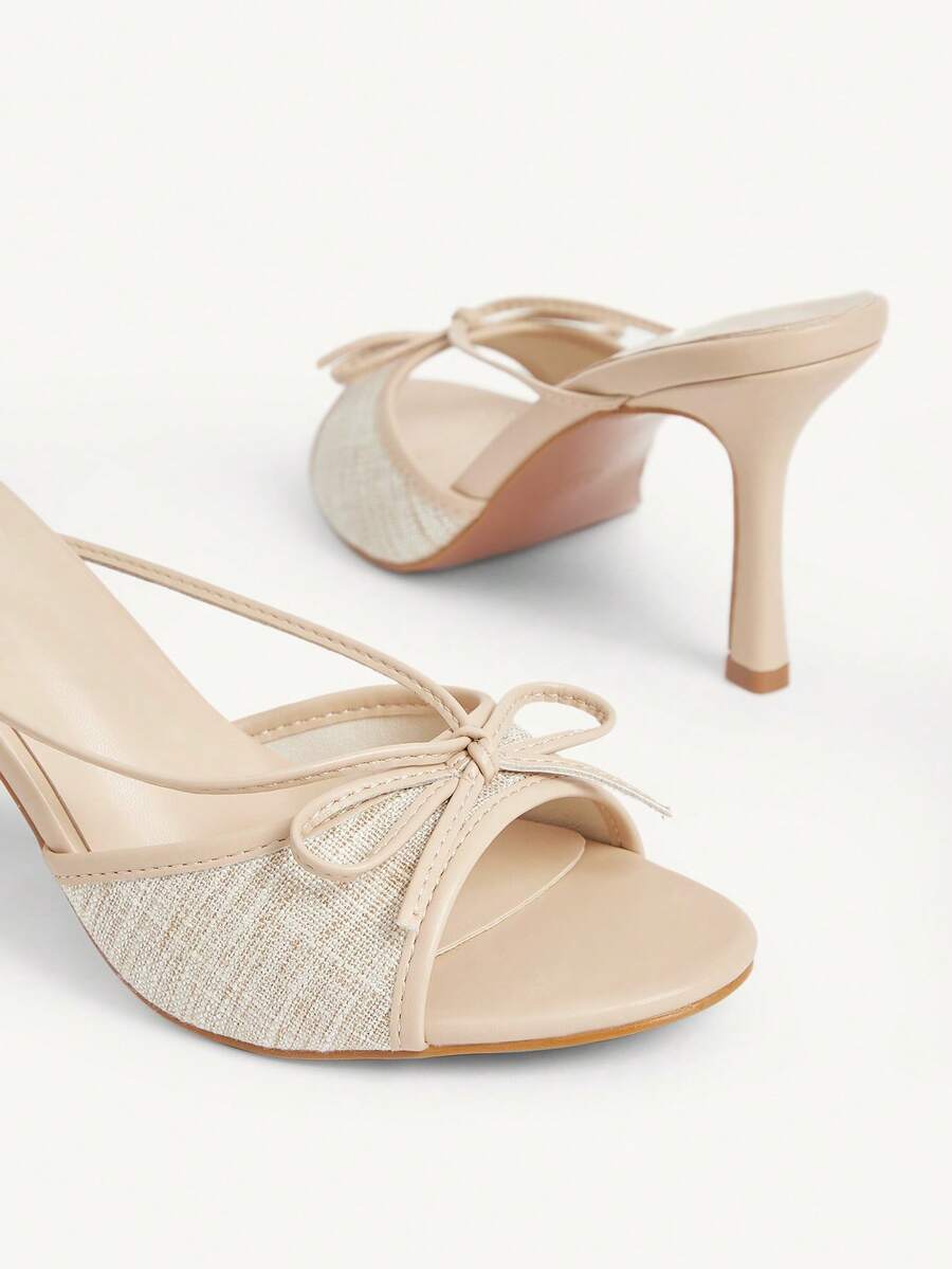 Elegant high heel sandals with romantic bow strap and slim stiletto heel for party and wedding occasions.
