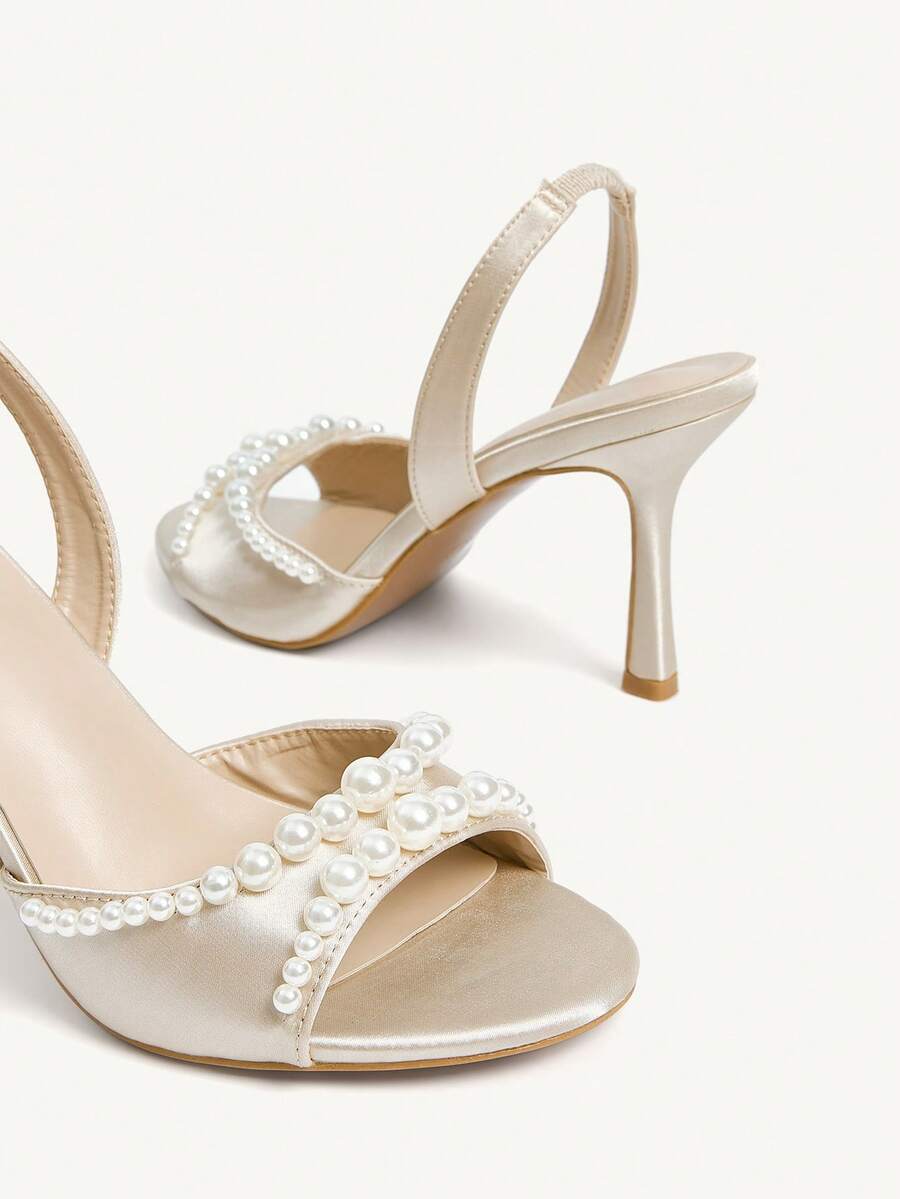 Elegant women's satin high heel sandals with pearl embellishments, stiletto heels, and slingback straps for bridal and wedding wear.