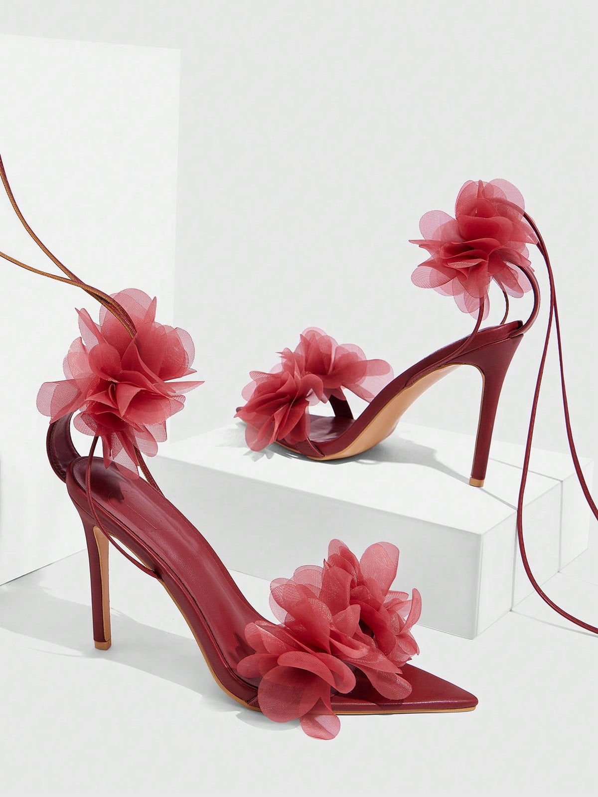 Women's open toe heeled sandals featuring 3D floral decor, satin lace-up ankle straps, and stiletto high heels.