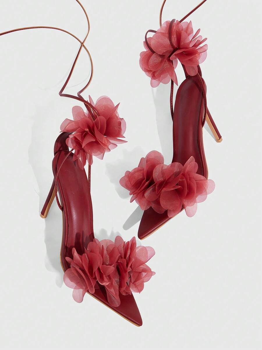 Women's open toe heeled sandals featuring 3D floral decor, satin lace-up ankle straps, and stiletto high heels.