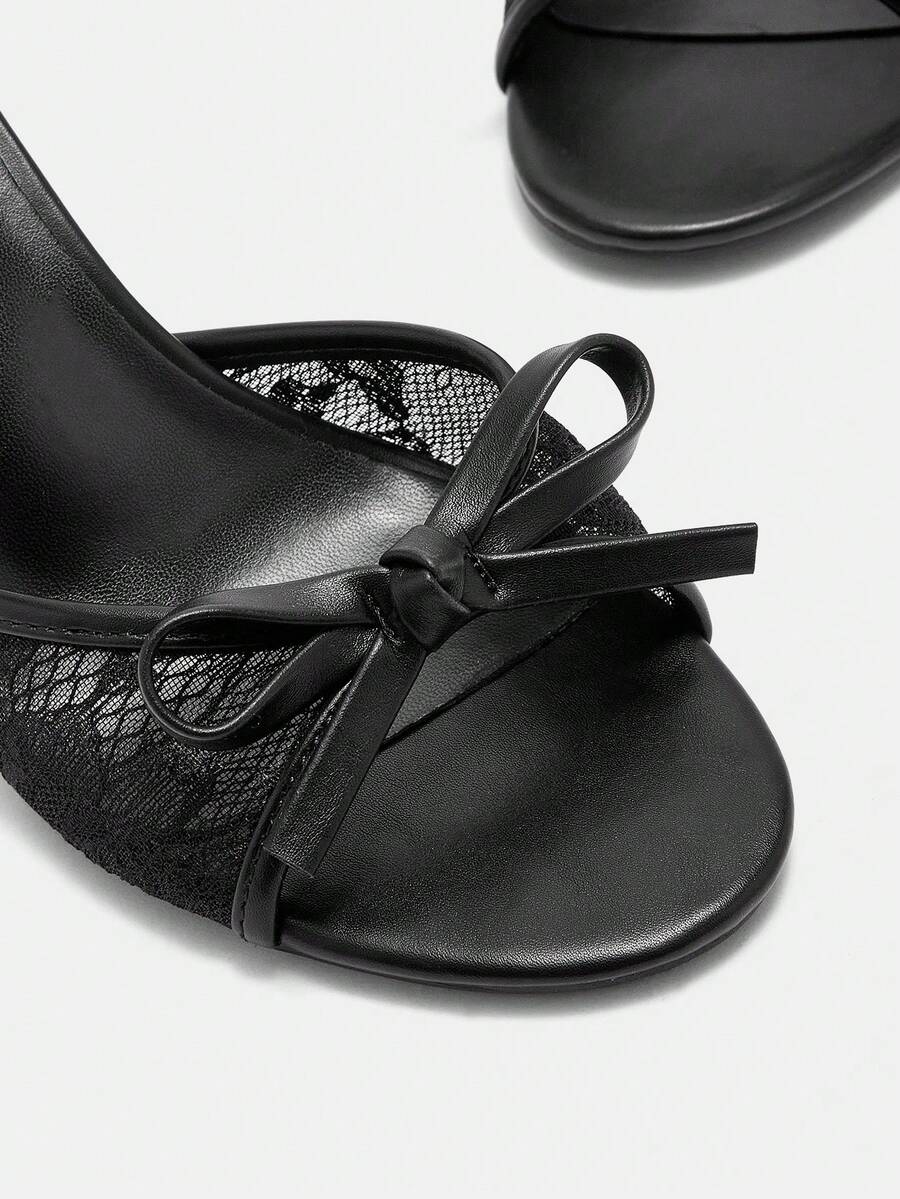 Women's black lace slip-on mule sandals featuring a high stiletto heel, open toe, and bow embellishment.