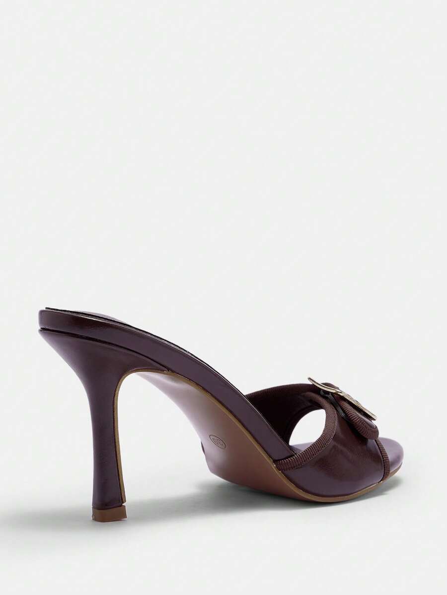 Women's brown leopard print high heel mule sandals with gold-tone buckle and grommet eyelet accents.