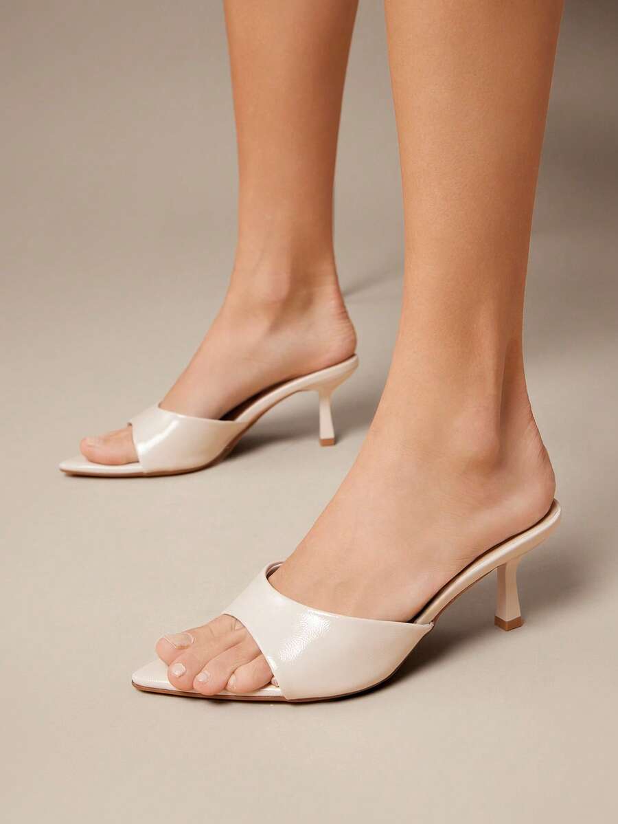 Black pointy toe kitten heel shoes for women featuring a sleek cut out mule design and glossy patent leather finish.