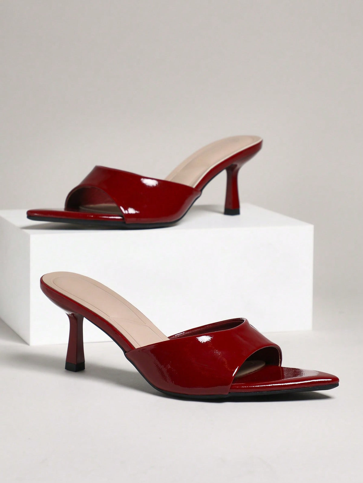 Black pointy toe kitten heel shoes for women featuring a sleek cut out mule design and glossy patent leather finish.