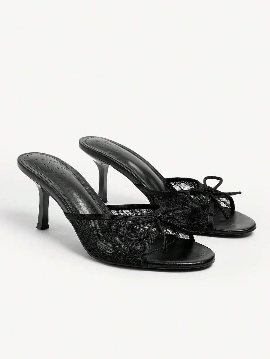 Open toe high heel slide sandals featuring lace details and a bow accent on the upper strap.