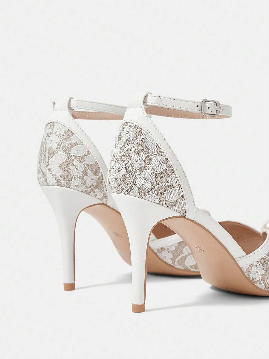 Beige high heel sandals with delicate lace overlay, pearl embellishments, stiletto heel, and adjustable ankle strap for bride and wedding party wear.