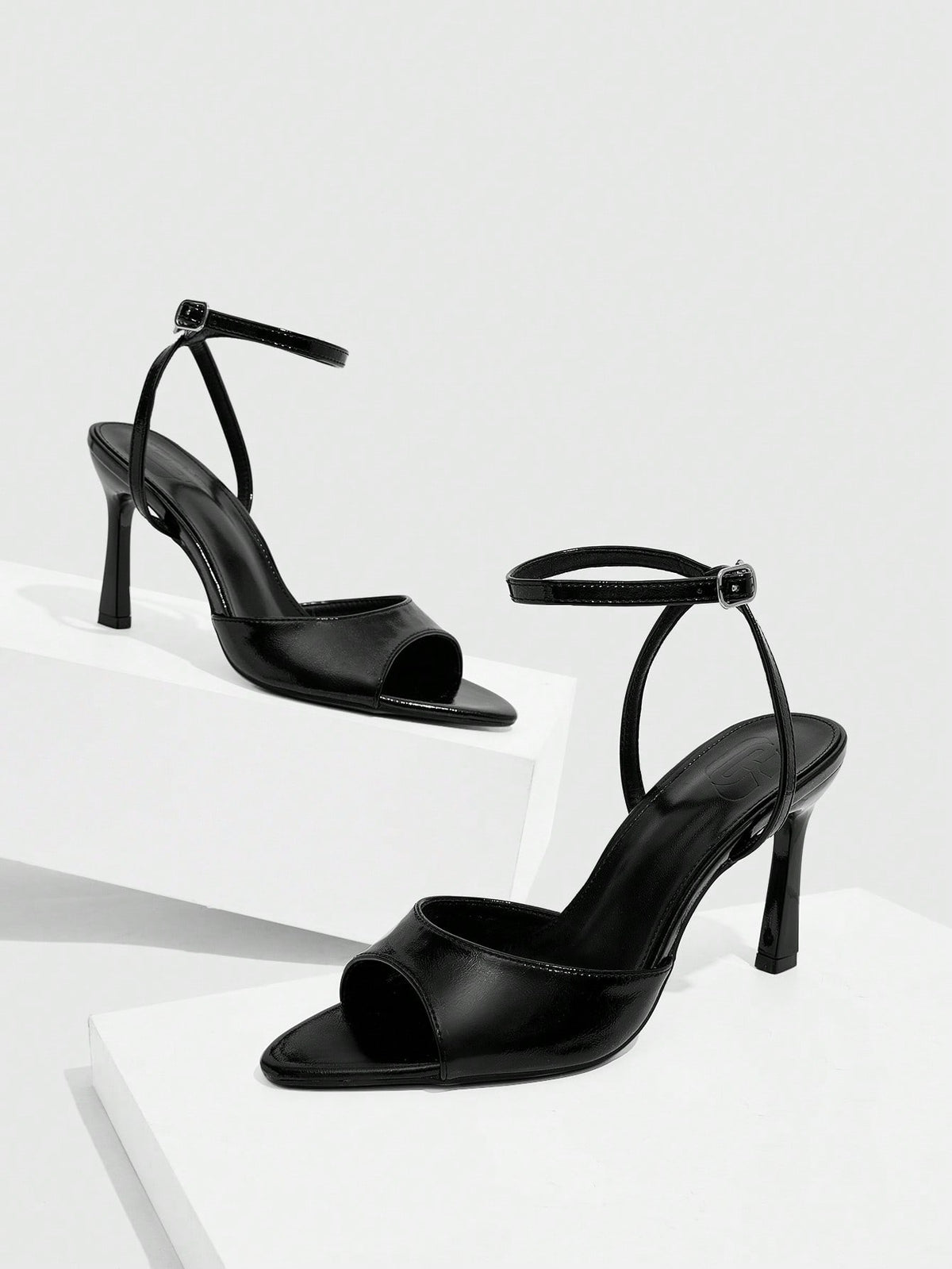 Pair of women's black high heel sandals with open toe design, slim stiletto heel, and adjustable ankle buckle strap.