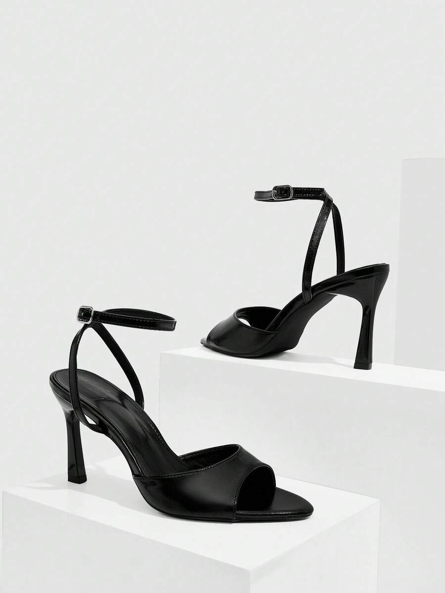 Pair of women's black high heel sandals with open toe design, slim stiletto heel, and adjustable ankle buckle strap.