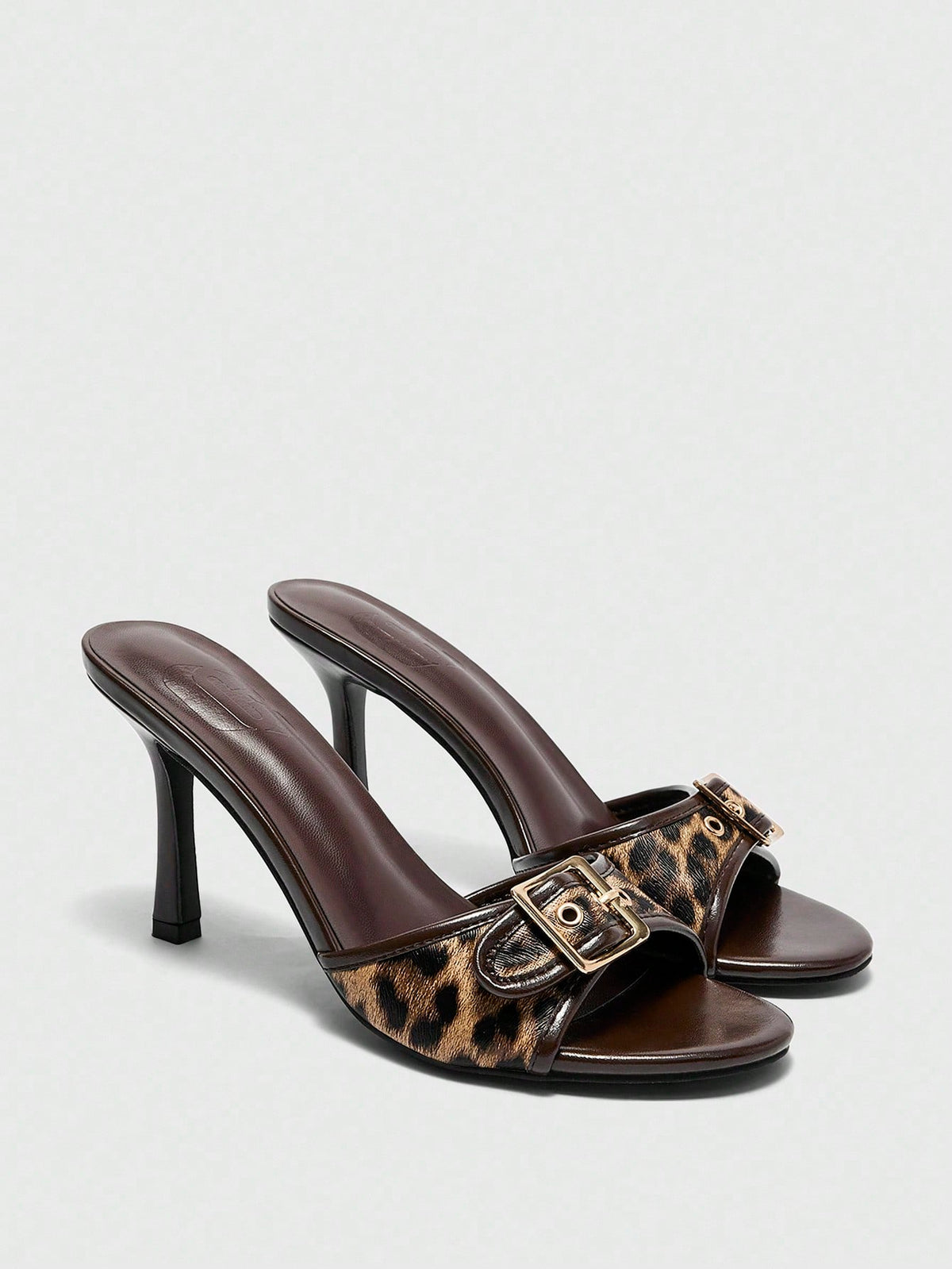 Women's brown leopard print high heel mule sandals with gold-tone buckle and grommet eyelet accents.
