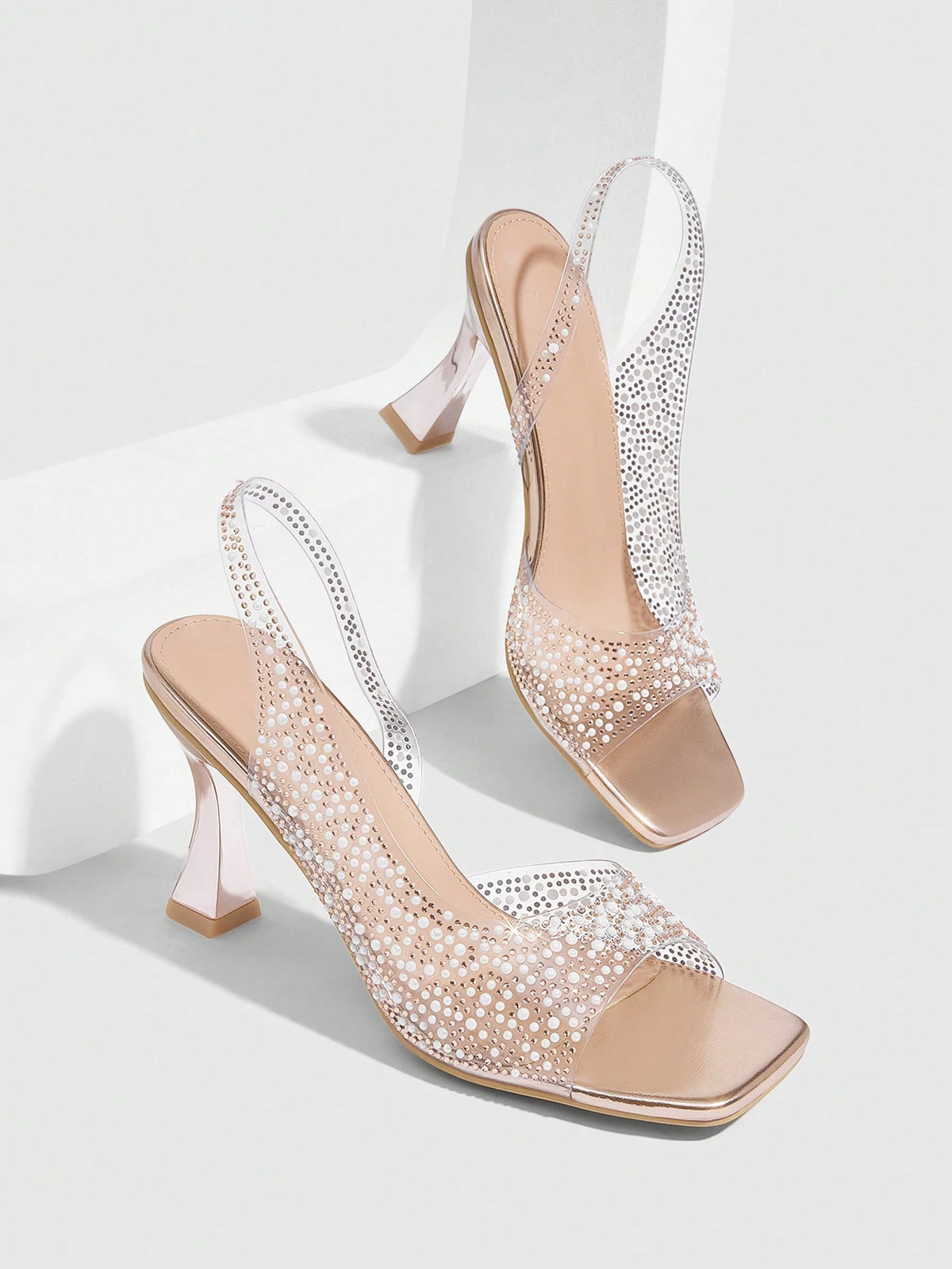 Women's square toe heeled sandals with clear straps, sparkling rhinestone embellishments, and a high pyramid heel.