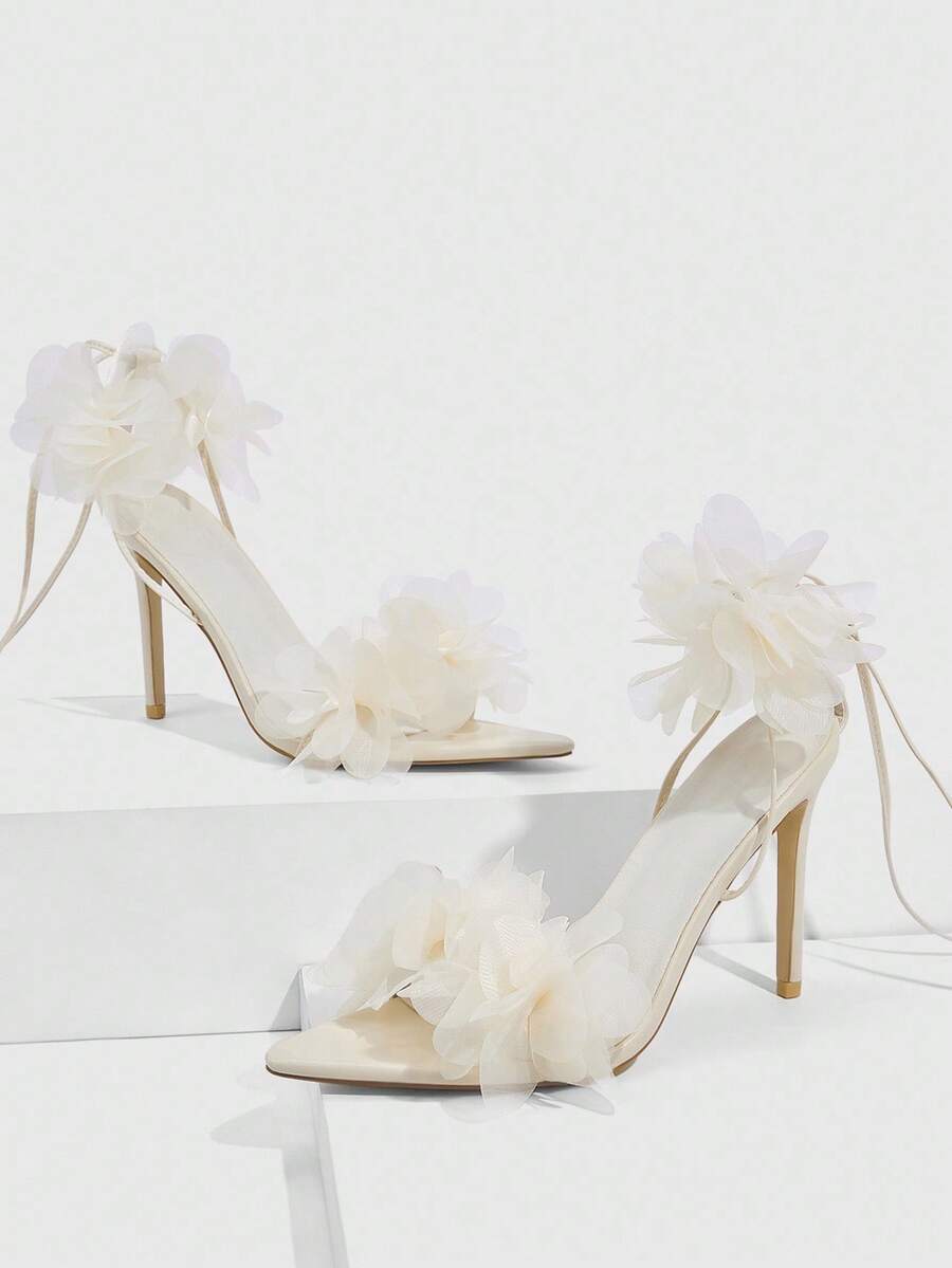 Women's open toe heeled sandals featuring 3D floral decor, satin lace-up ankle straps, and stiletto high heels.