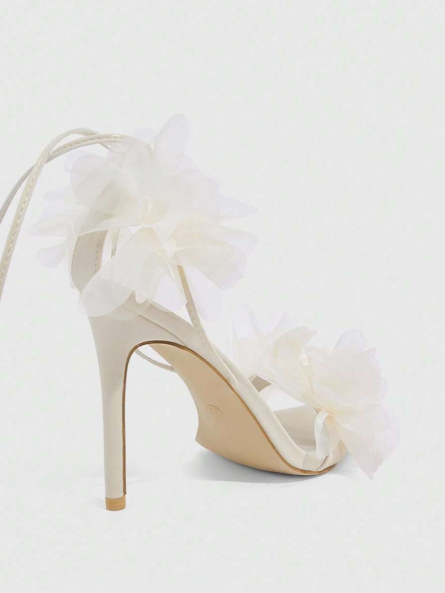Women's open toe heeled sandals featuring 3D floral decor, satin lace-up ankle straps, and stiletto high heels.