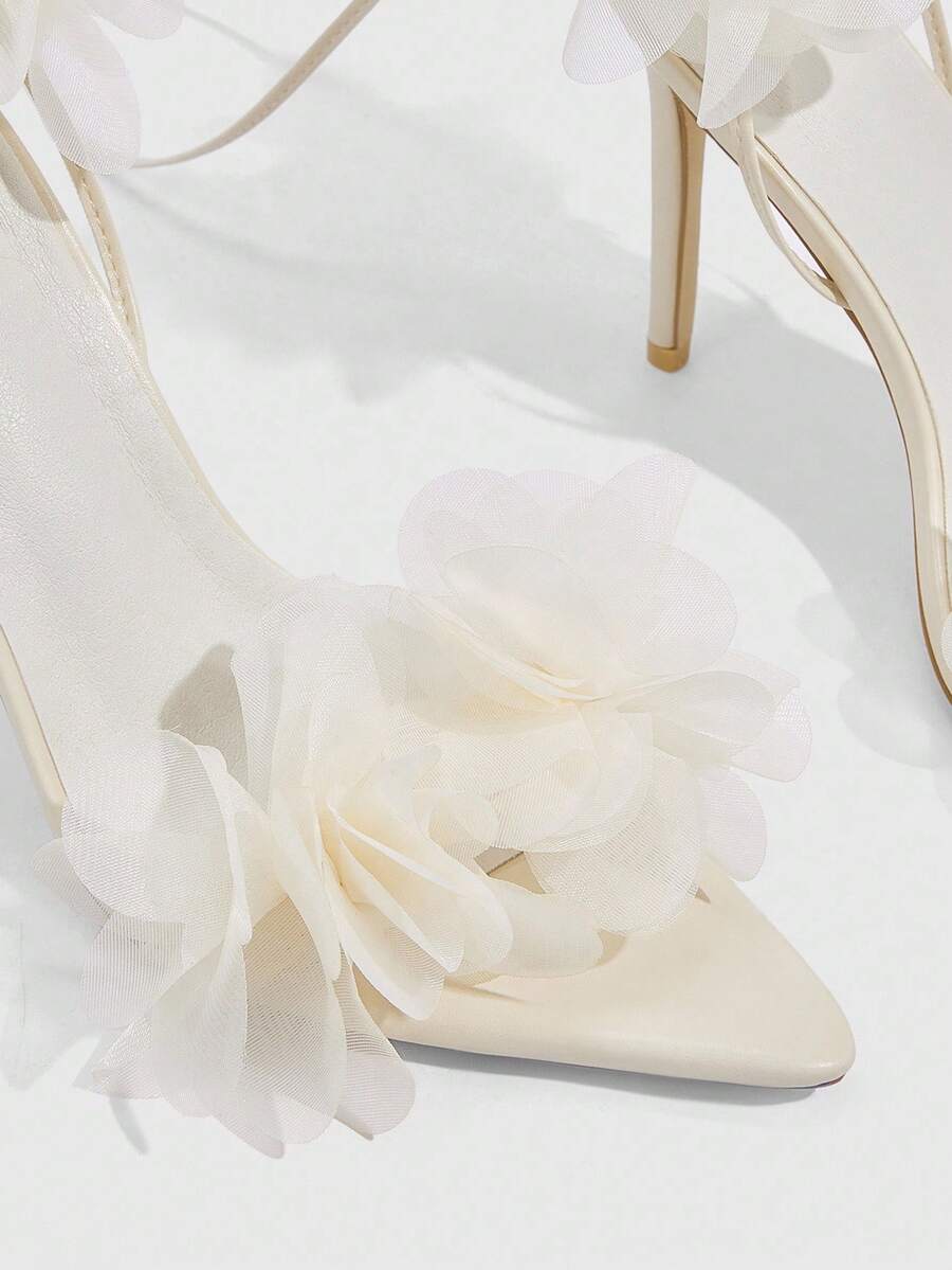 Women's open toe heeled sandals featuring 3D floral decor, satin lace-up ankle straps, and stiletto high heels.