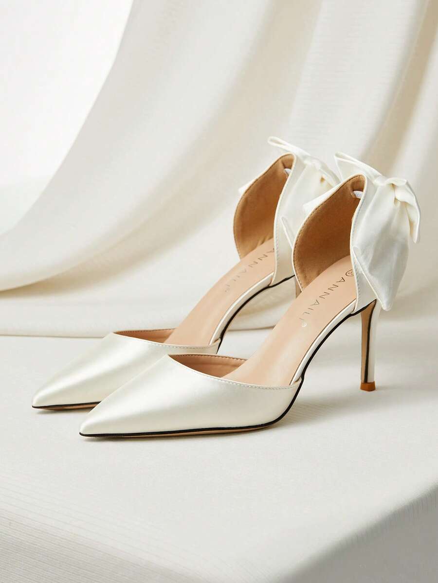 White satin bridal high heels with an elegant bow knot accent, pointed toe, and slingback stiletto heel for weddings and formal events.
