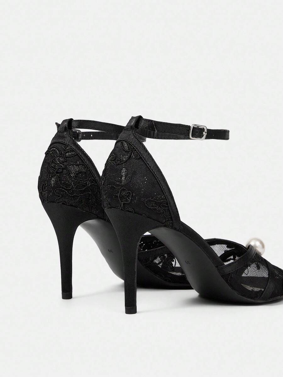 Beige high heel sandals with delicate lace overlay, pearl embellishments, stiletto heel, and adjustable ankle strap for bride and wedding party wear.