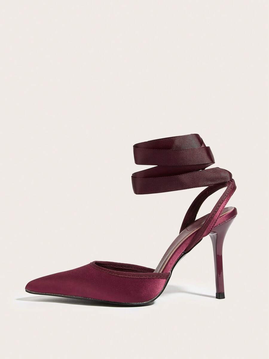 Burgundy satin pointed toe stiletto high heel pumps with a backless design and delicate bow accent.