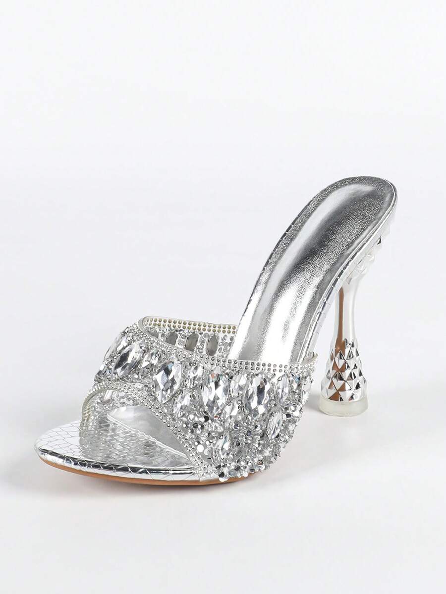 Women's metallic-plated high heeled sandals with shining rhinestone accents, sculptural stiletto heel, and open round toe.