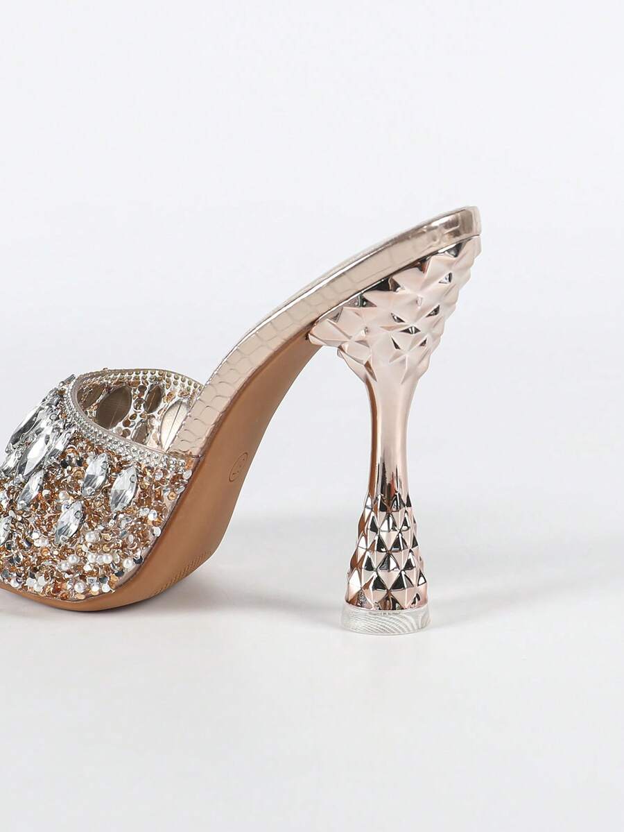 Women's metallic-plated high heeled sandals with shining rhinestone accents, sculptural stiletto heel, and open round toe.