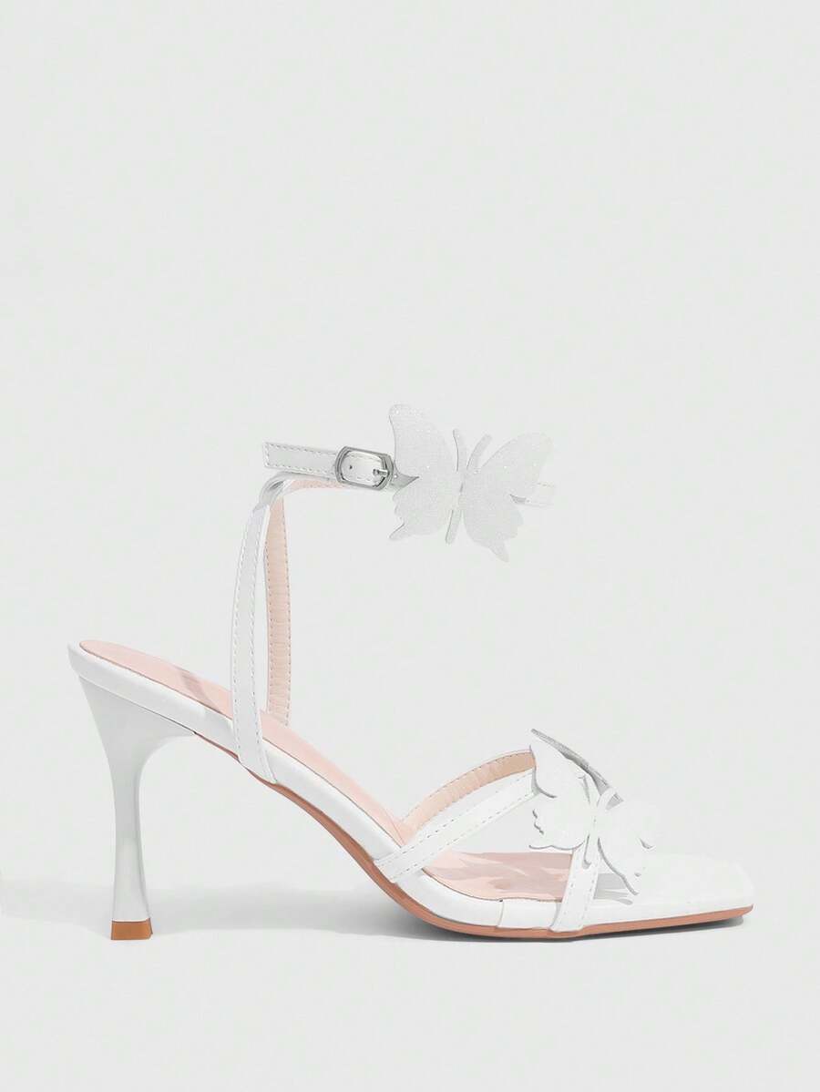Glossy gold high heels featuring a sculptural heel, open-toe design, ankle strap buckle closure, and sparkling rhinestone butterfly embellishments.