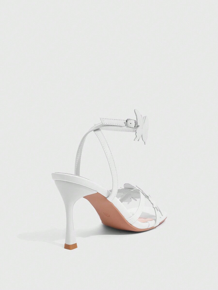 Glossy gold high heels featuring a sculptural heel, open-toe design, ankle strap buckle closure, and sparkling rhinestone butterfly embellishments.