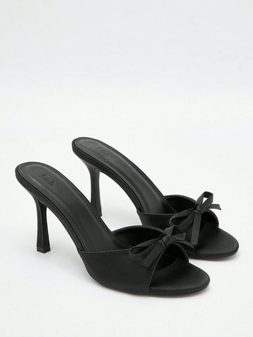 Pair of women's open toe stiletto heeled sandals crafted in satin with a bow accent