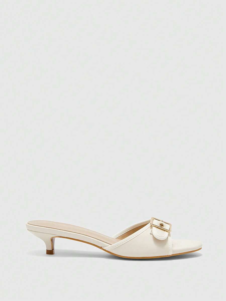 Beige women's slip-on kitten heel slide sandals featuring an accent buckle with grommet eyelets.