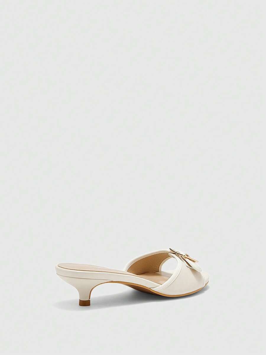 Beige women's slip-on kitten heel slide sandals featuring an accent buckle with grommet eyelets.
