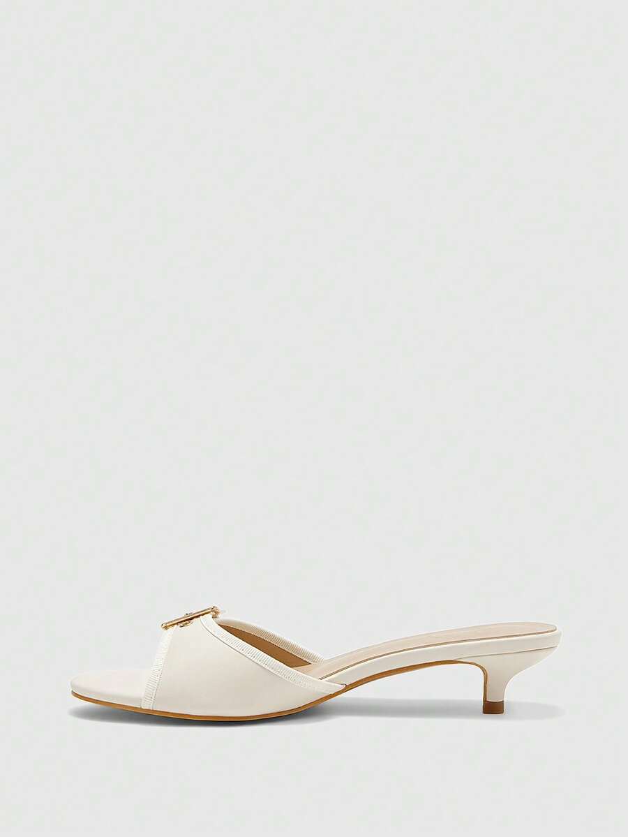 Beige women's slip-on kitten heel slide sandals featuring an accent buckle with grommet eyelets.