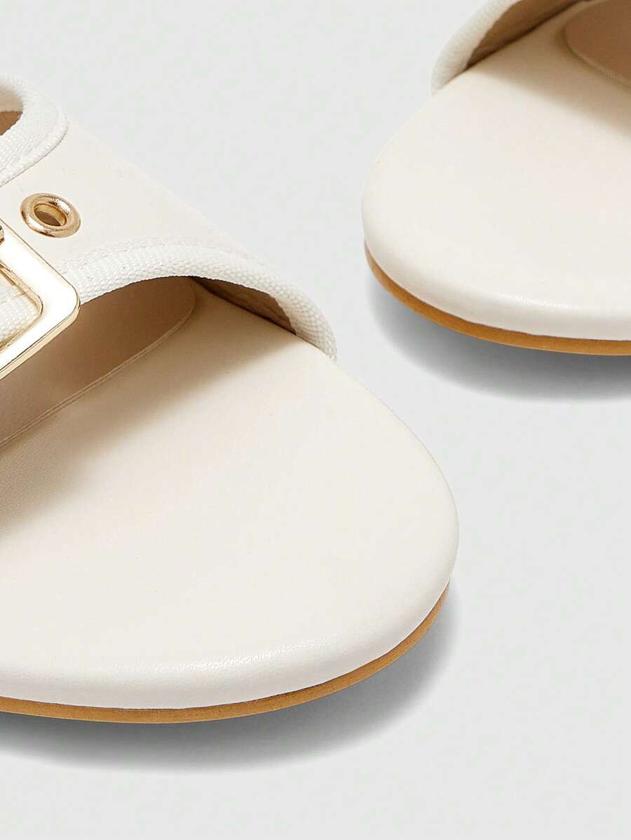 Beige women's slip-on kitten heel slide sandals featuring an accent buckle with grommet eyelets.