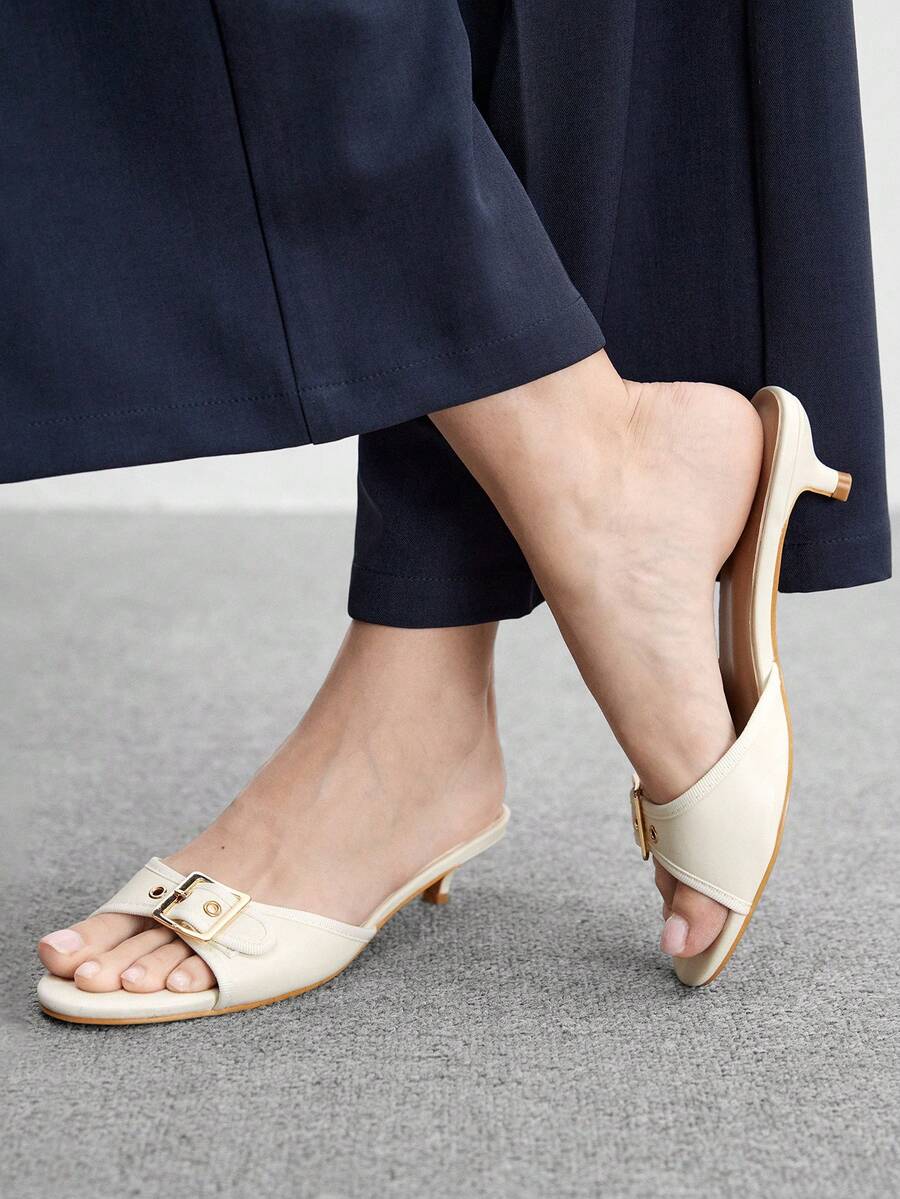 Beige women's slip-on kitten heel slide sandals featuring an accent buckle with grommet eyelets.