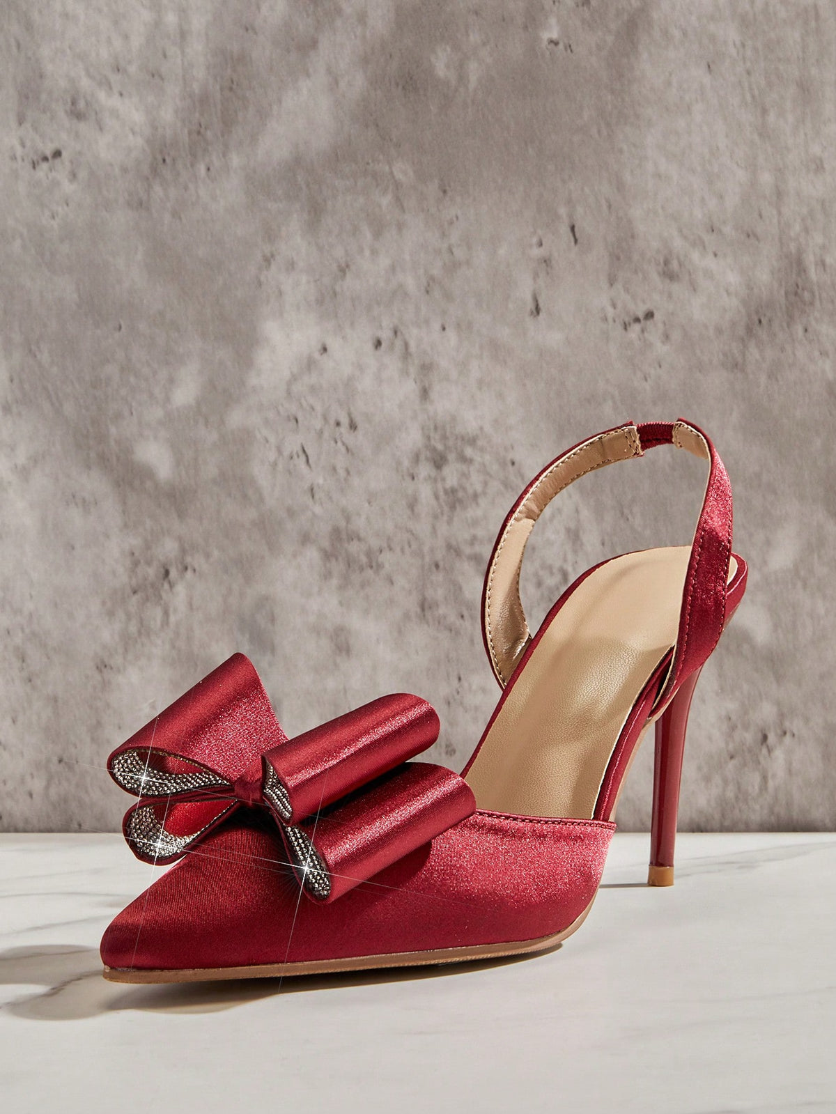Women's pointed toe stiletto heel slingback pumps in chocolate brown with double metal buckle strap details.