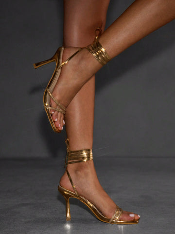 Red shiny patent leather stiletto high heel sandals featuring a square toe and criss-cross ankle strap with buckle closure.