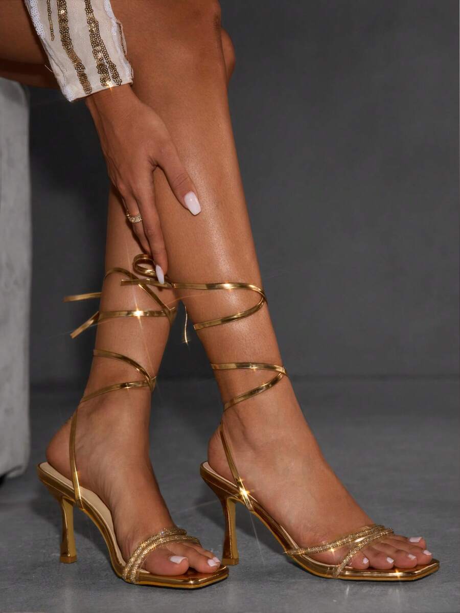 Red shiny patent leather stiletto high heel sandals featuring a square toe and criss-cross ankle strap with buckle closure.