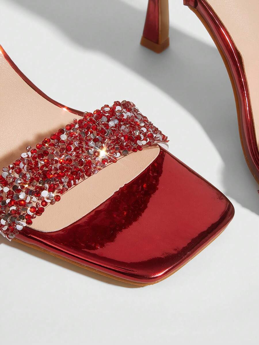 Red shiny patent leather stiletto high heel sandals featuring a square toe and criss-cross ankle strap with buckle closure.