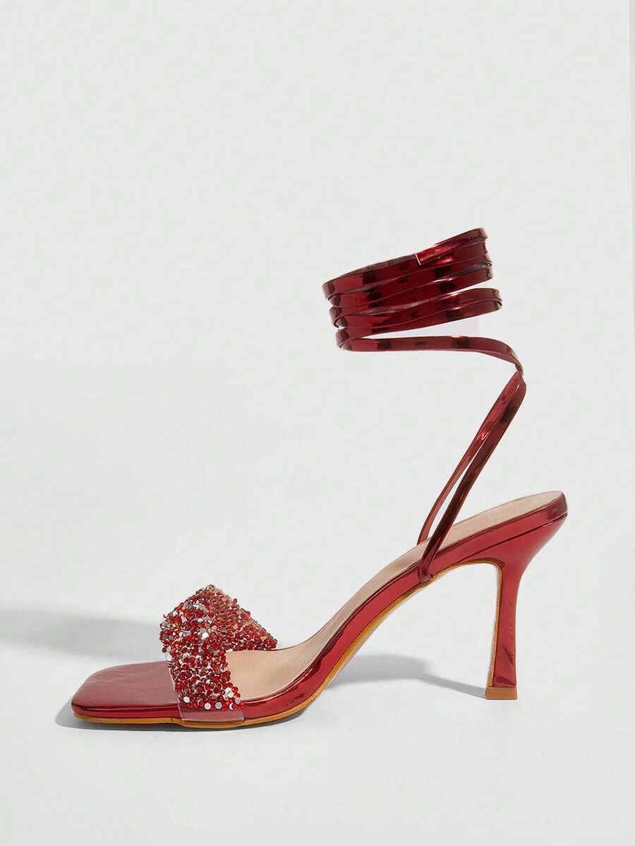 Red shiny patent leather stiletto high heel sandals featuring a square toe and criss-cross ankle strap with buckle closure.