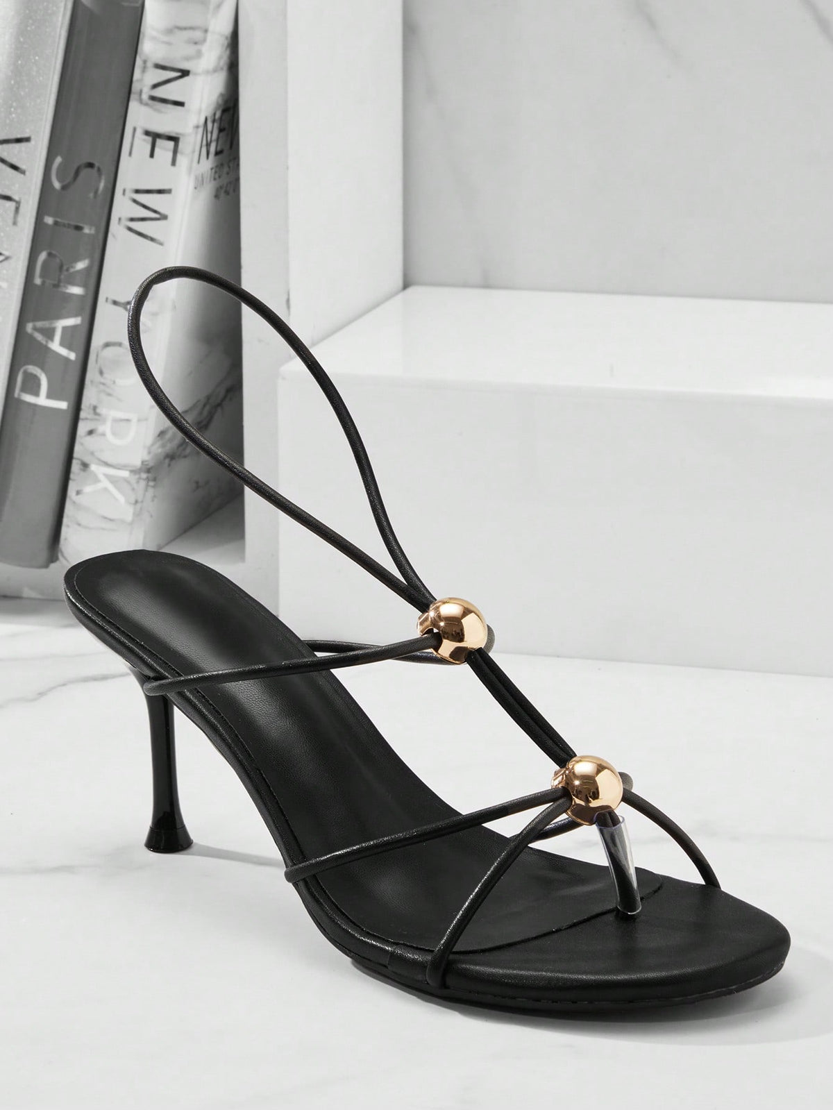 Women's strappy stiletto heel sandals crafted in vegan PU leather featuring open toe design and metallic bead accents.