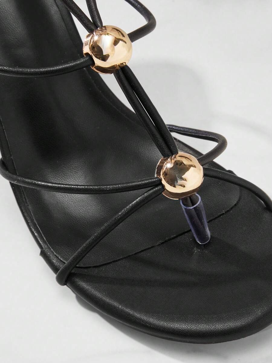 Women's strappy stiletto heel sandals crafted in vegan PU leather featuring open toe design and metallic bead accents.