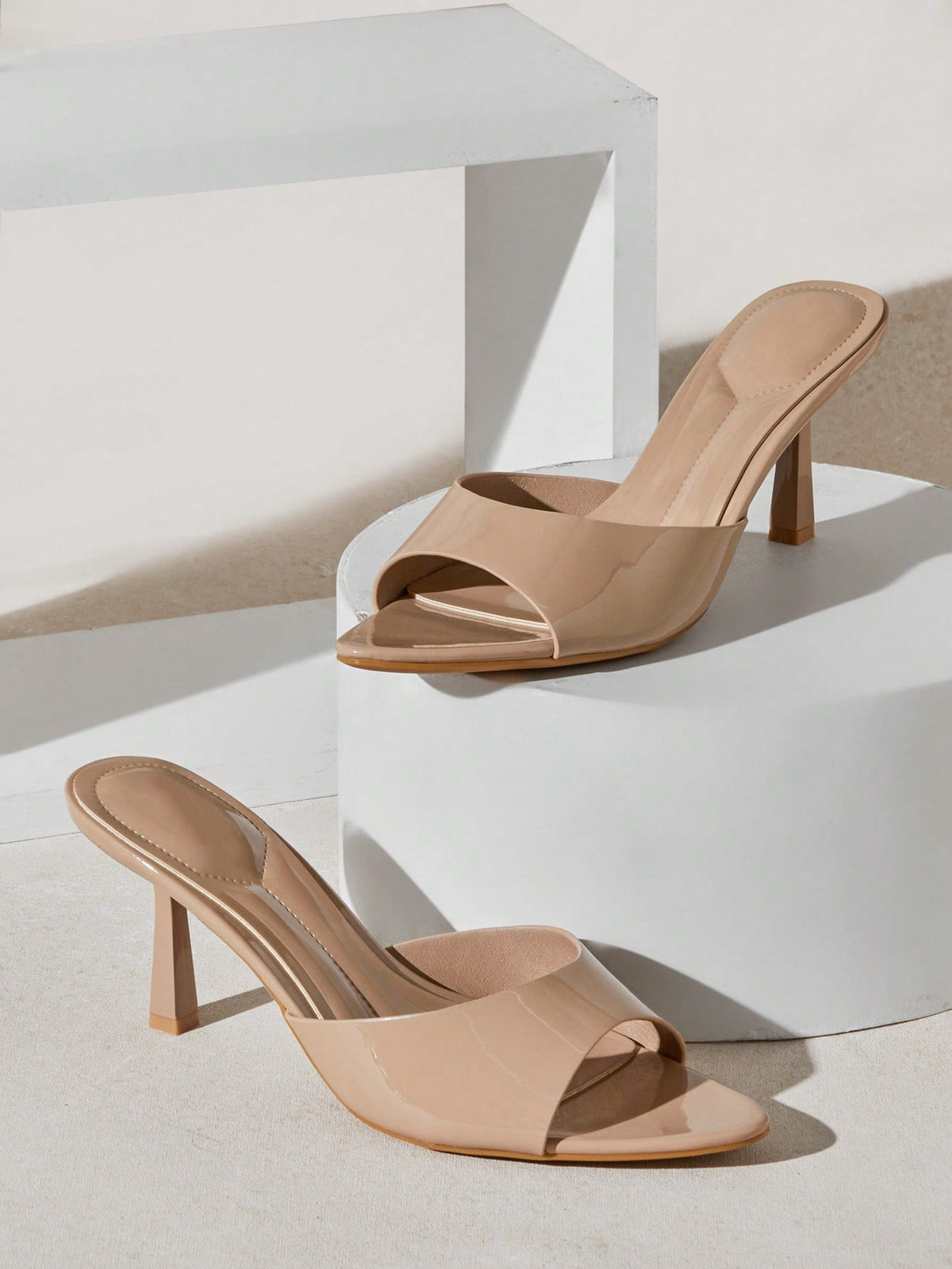 Black pointy toe kitten heel shoes for women featuring a sleek cut out mule design and glossy patent leather finish.