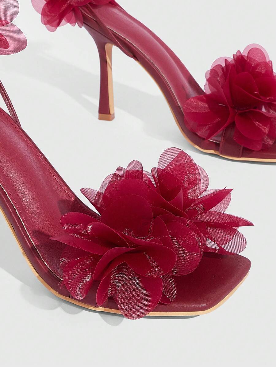 Women's open toe heeled sandals featuring 3D floral decor, satin lace-up ankle straps, and stiletto high heels.