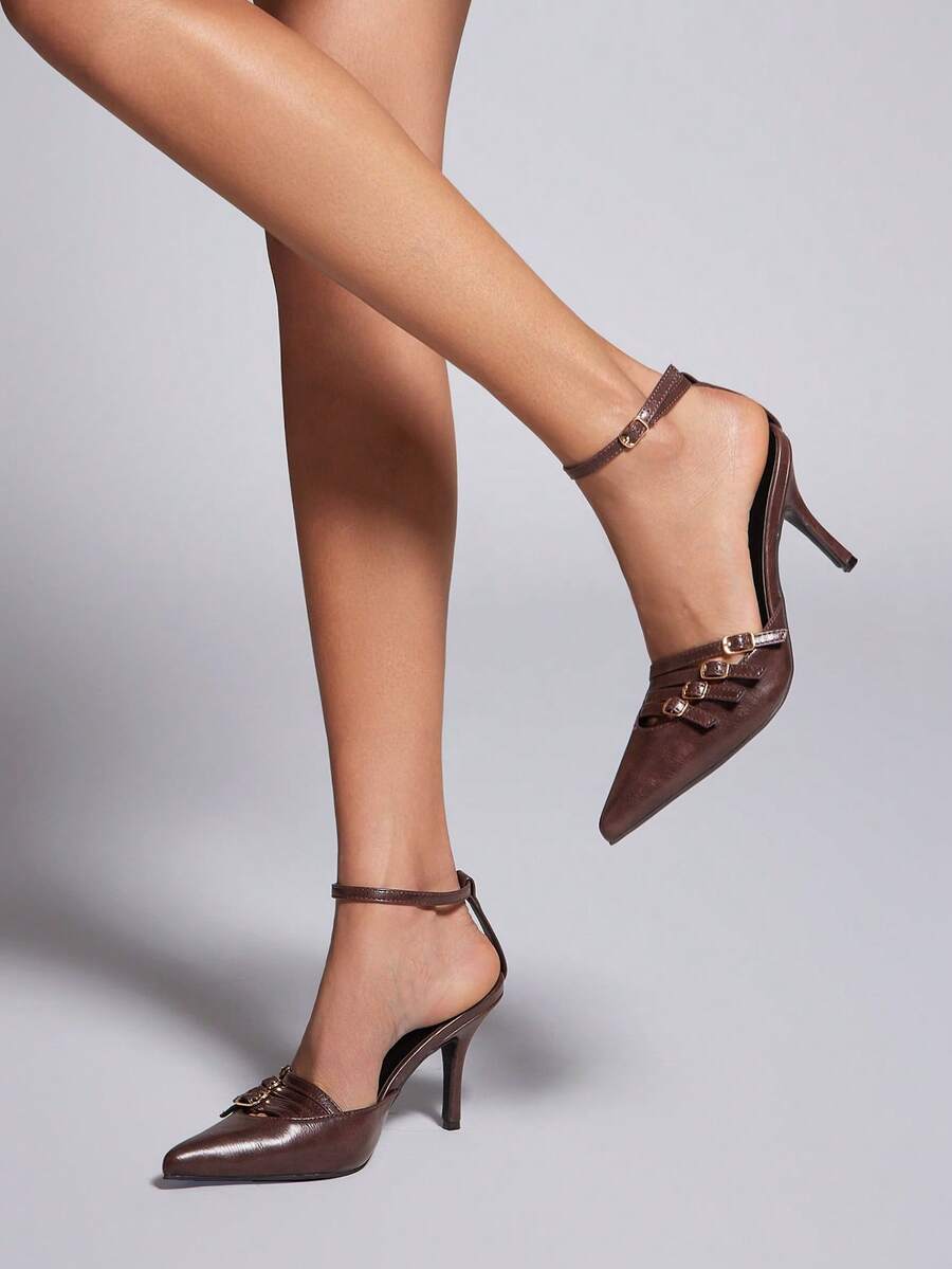 Women's pointed toe stiletto heel slingback pumps in chocolate brown with double metal buckle strap details.