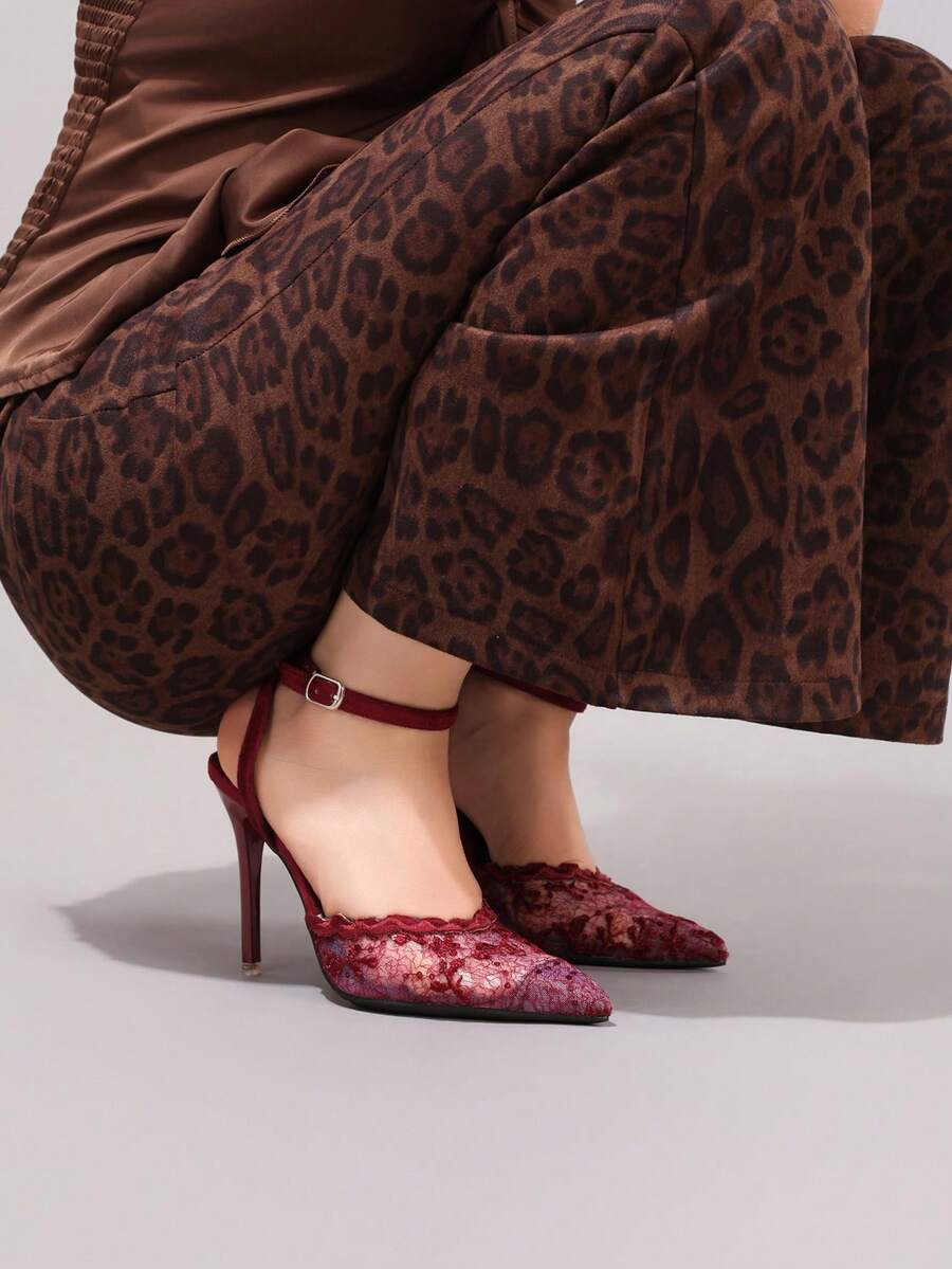 Lace embroidered high heels with thin stiletto heel, pointed toe, rhinestone embellishments, and ankle strap buckle closure.