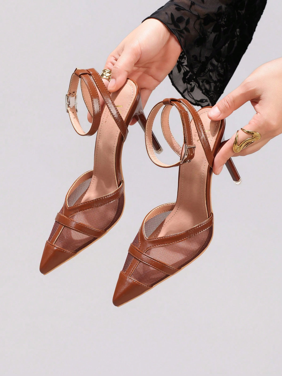 Lace embroidered high heels with thin stiletto heel, pointed toe, rhinestone embellishments, and ankle strap buckle closure.
